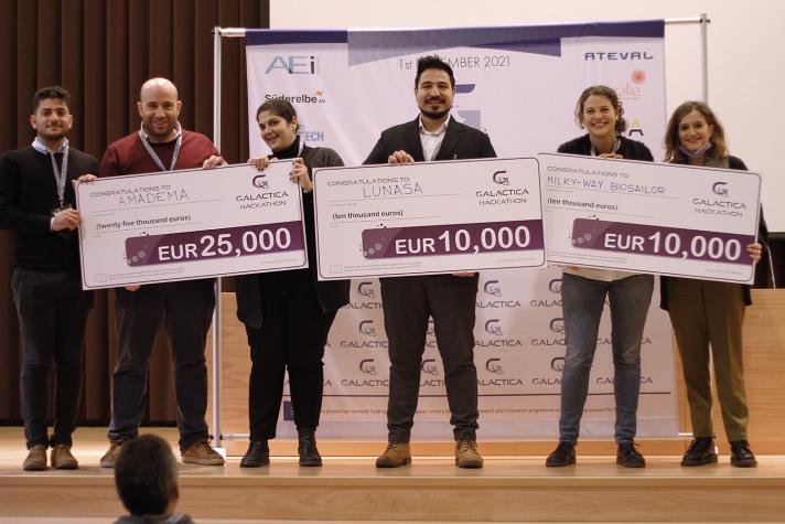 Winning teams of the 2nd GALACTICA hackathon proudly posing with checks for their respective prize money - €25 thousand for the champions AMADEMA, and €10 thousand each for LUNASA and MILKY WAY BIOSAILOR.