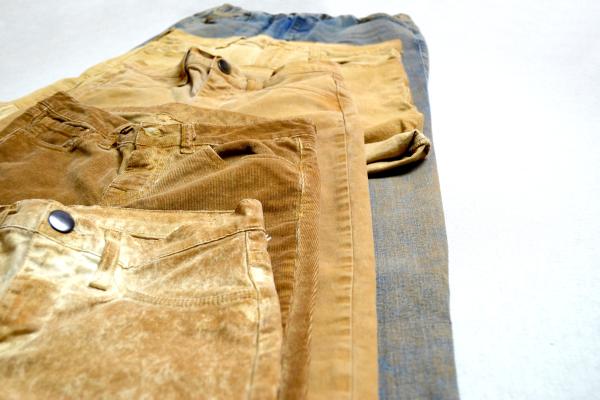 Picture showing 4 different pants all brown or brownish laying on a hard base